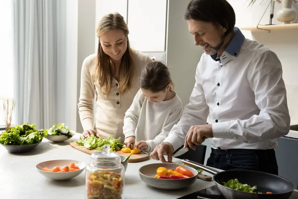 Happy couple and little daughter kid cooking healthy meal together — стоковое фото