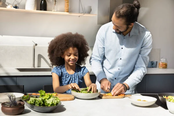 Happy African father and cute daughter girl preparing fresh salad — Stockfoto