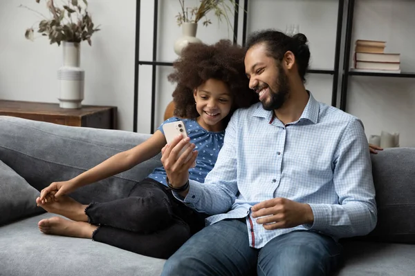 Happy dad and teen daughter kid using smartphone at home — Stockfoto