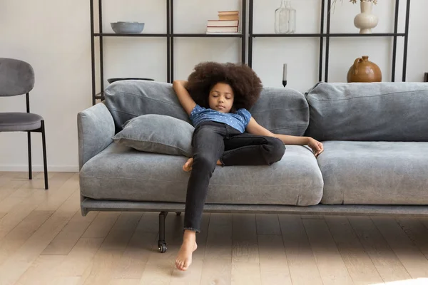 Friedliches afrikanisches Mädchen mit lockigem Haar ruht auf Couch — Stockfoto