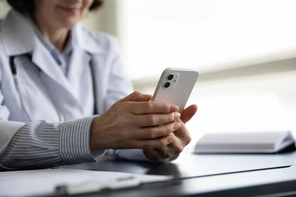 Primer plano médico femenino de mediana edad utilizando el teléfono celular. —  Fotos de Stock