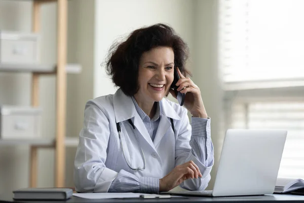 Gelukkige middelbare leeftijd vrouwelijke arts multitasking in kliniek. — Stockfoto
