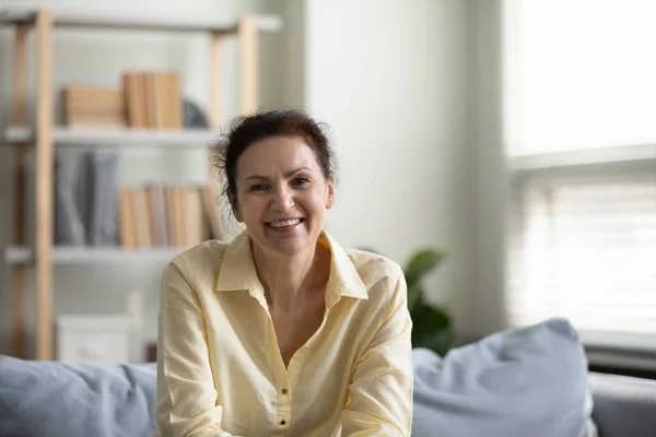 Portrait of happy mature homeowner siting on sofa. — Stock Photo, Image