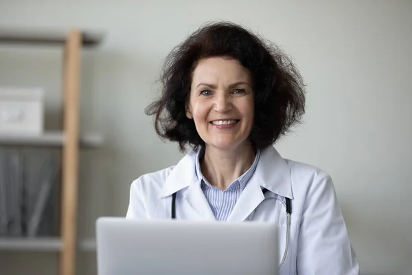 Portrait of smiling trusted older doctor working in office. — Stockfoto
