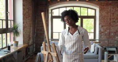 Yetenekli genç siyahi kadın ressam yağlı boya tablo üzerinde çalışıyor.