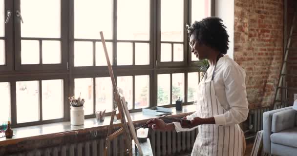 Inspired young African American female artist paint picture on easel — 图库视频影像