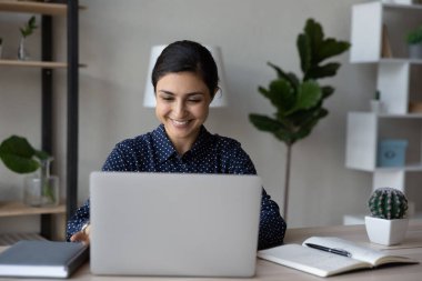 Masadaki dizüstü bilgisayarda yazan mutlu Hintli ofis çalışanı.
