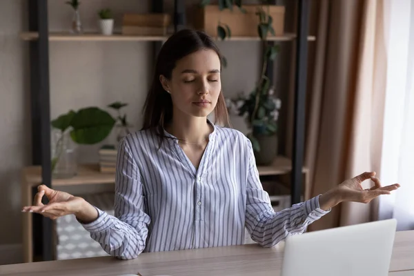 Peaceful calm woman meditating at office workplace with computer — Stock Photo, Image