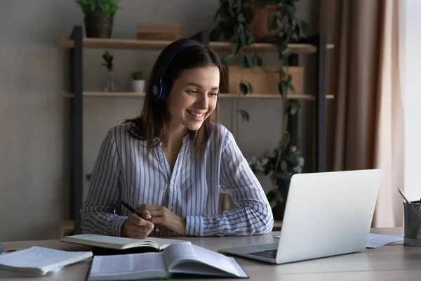 Glad tusenårig student flicka i hörlurar studerar hemifrån — Stockfoto