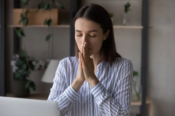 Religious millennial business woman praying at workplace — Stockfoto