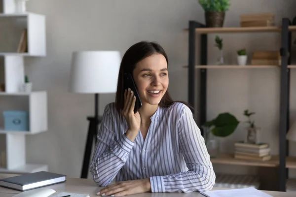 Happy office employee talking on mobile phone at office table — Stock Photo, Image