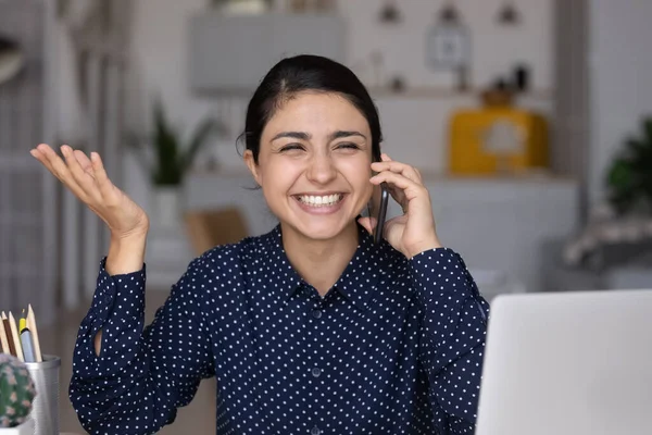Happy Indian girl speaking on cellphone at laptop — Stockfoto
