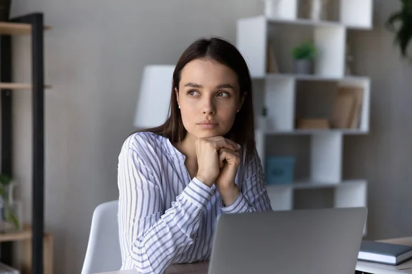 Empleado serio y reflexivo sentado en la mesa con el portátil —  Fotos de Stock