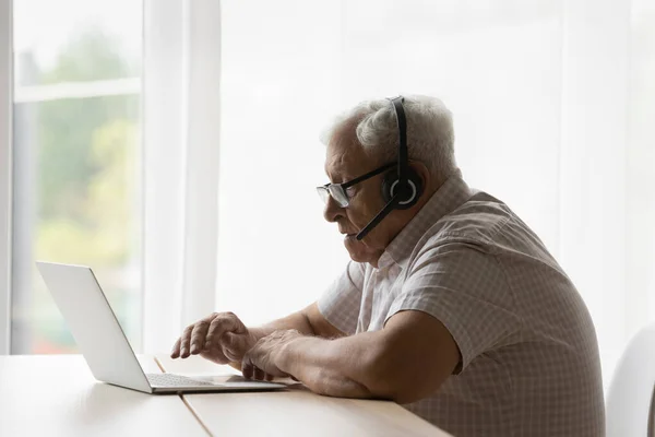 Concentrated 80s old retired man holding video call conversation. — стоковое фото