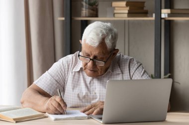 Konsantre olmuş yaşlı adam çevrimiçi kurslara çalışıyor..