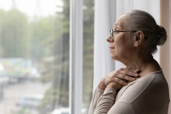 Depressed elderly mature woman in eyewear looking in distance. — Stockfoto