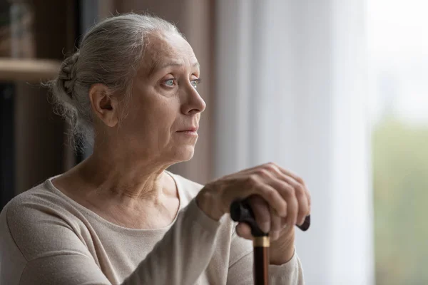 Gefrustreerde vrouw van middelbare leeftijd met een loophandicap die op afstand kijkt. — Stockfoto