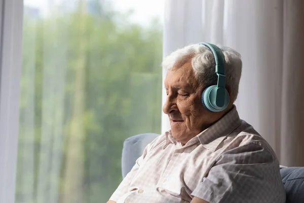 Счастливый беззаботный пожилой человек слушает музыку в наушниках. — стоковое фото