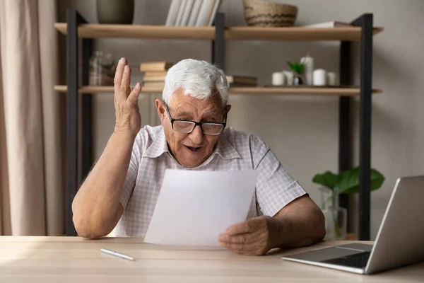 Happy old mature man feeling surprised reading paper document. — стоковое фото