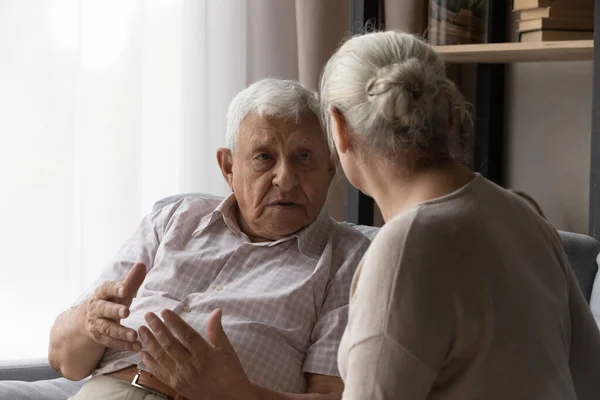 Stressed old man sharing problems with compassionate elderly wife. — стоковое фото