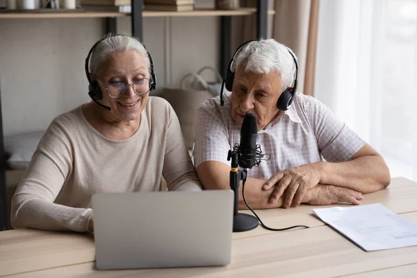 Joyful focused old couple recording voice at home. — стоковое фото