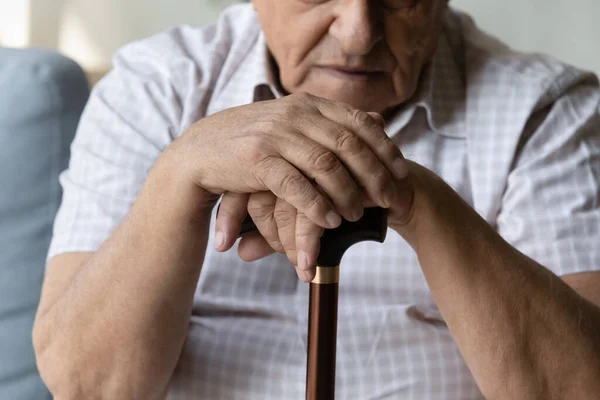 Closeup cropped old man holding hands on walking cane. — стоковое фото