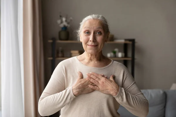 Smiling middle aged woman holding folded hands on chest. — Foto Stock