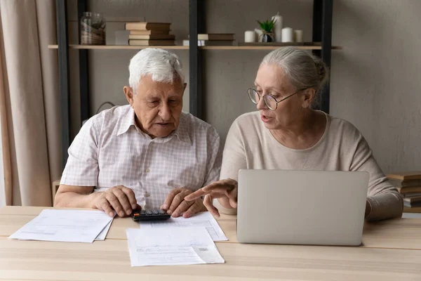 Concentrated middle aged couple managing household budget. — Stock Fotó