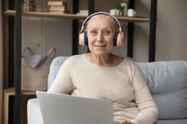 Portrait of smiling beautiful mature retired hoary woman in headphones. — Stock Photo, Image