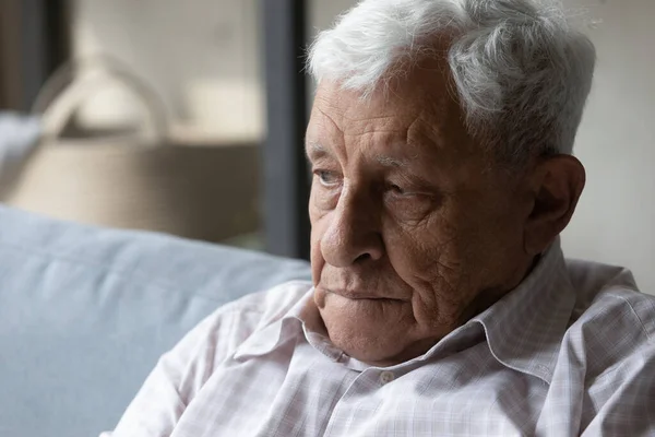 Lost in negative thoughts unhappy old man sitting on couch. – stockfoto