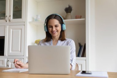 Parlak kablosuz kulaklıklı neşeli öğrenci kız Webinar 'ı izliyor.