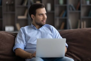 Hayalperest adam dizüstü bilgisayardan uzaklaşıp koltukta oturuyor.