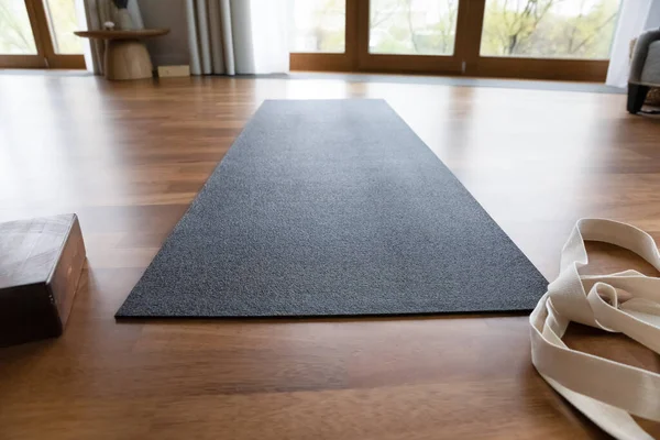 Dark grey yoga mat and strap in empty room — Stockfoto