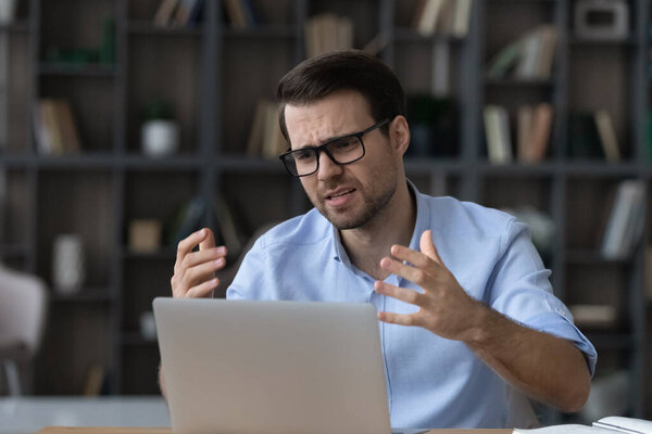 Head shot unhappy confused businessman in glasses looking using laptop