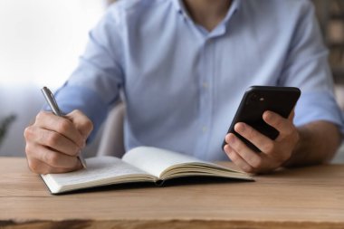 Yakın mesafeden kesilen iş adamı akıllı telefon tutuyor, bilgi yazıyor.