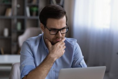 Gözlüklü düşünceli iş adamının dizüstü bilgisayar kullandığından emin.