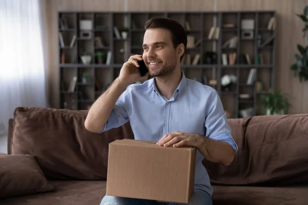 Uomo sorridente che fa una telefonata al servizio clienti, pacco ricevuto — Foto Stock