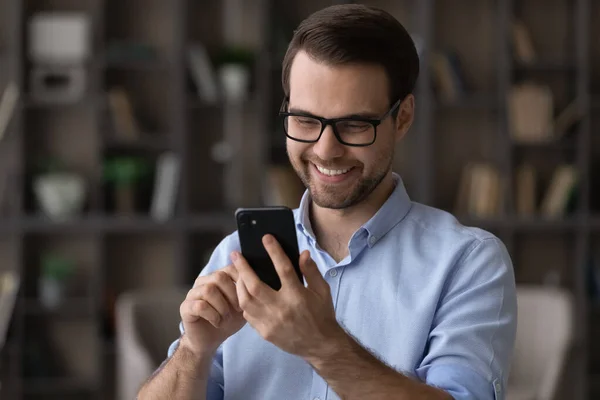 Head shot uomo sorridente con gli occhiali utilizzando smartphone, chatta online — Foto Stock