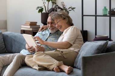 Dijital tablet kullanan mutlu 60 'lı yaşlardaki aile çiftleri.