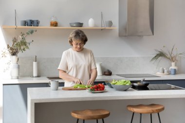 Modern mutfakta yemek pişiren yaşlı, mutlu kadın..