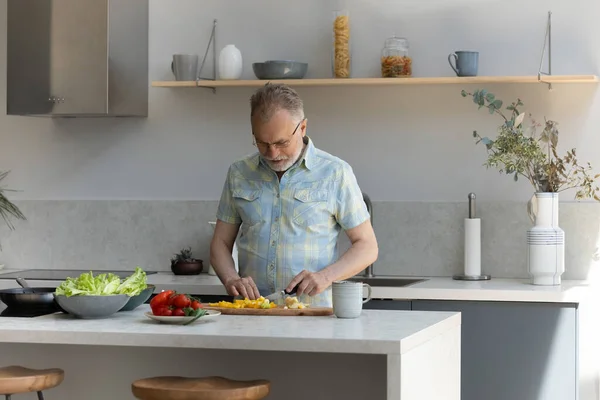 Щасливий середнього віку старший чоловік готує на кухні . — стокове фото