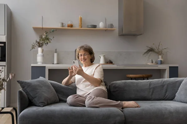 Entspannt glücklich alte Frau mit Handy zu Hause. — Stockfoto