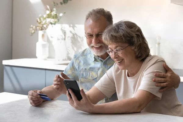 Happy elderly couple shopping in mobile application. — Stock Fotó