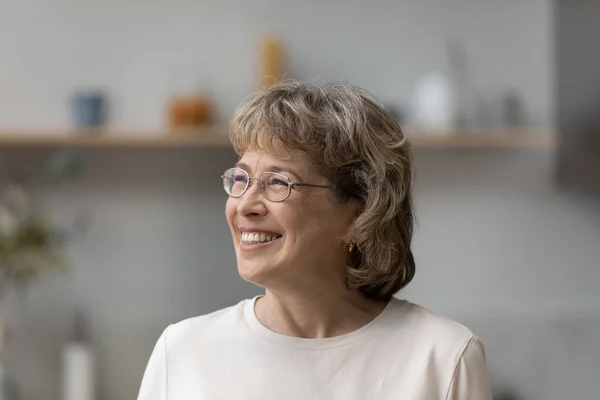 Joyful mature older 60s woman in eyeglasses looking in distance. — Foto Stock