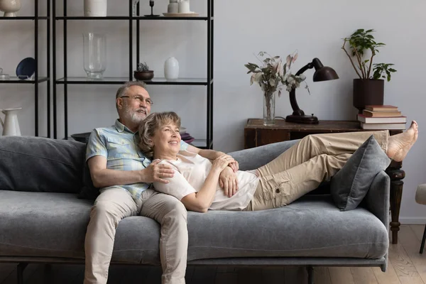 Relajado feliz pareja de edad que se relaja en el sofá acogedor. — Foto de Stock
