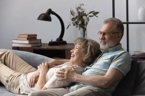 Affectionate middle aged couple resting on cozy sofa. — Stock Fotó