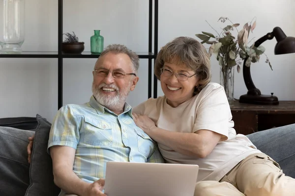 Happy bonding dreamy older couple using laptop. — Stock Fotó