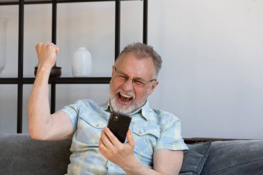 Aşırı neşeli orta yaşlı adam çevrimiçi piyango kazanmasını kutluyor..