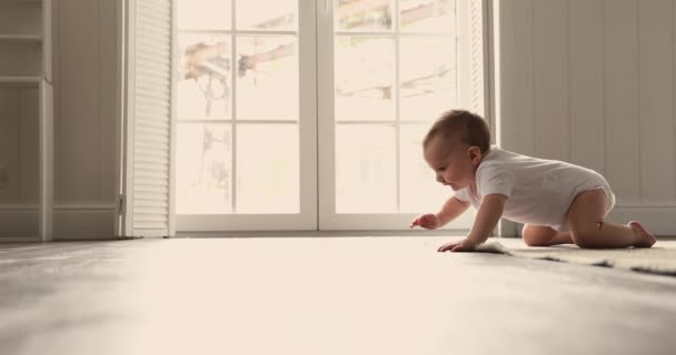 Little infant crawls on warm floor in room — стоковое видео