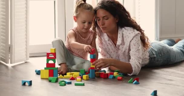 Jovem mãe jogar cubos de madeira multi colorido com filha pequena — Vídeo de Stock